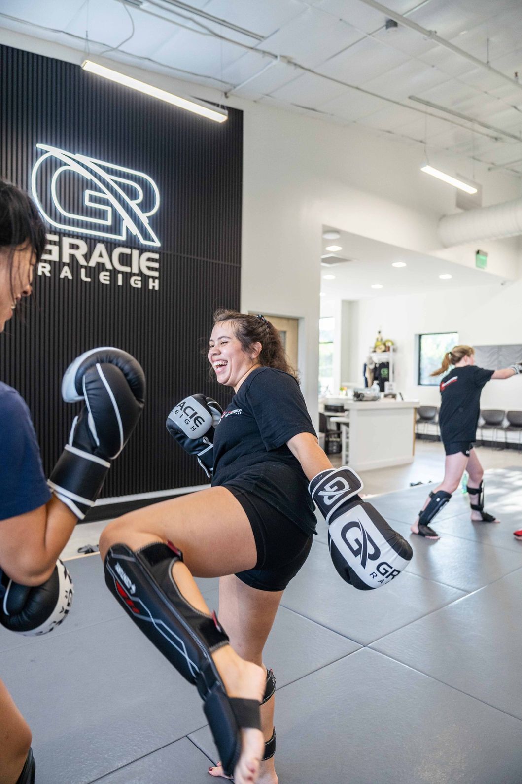 A group of women practicing pad work and striking combinations during a kickboxing fitness class at Gracie Raleigh.